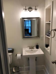 La salle de bains est pourvue d'un lavabo, d'un miroir et de toilettes. dans l'établissement Renovated Space Close To Downtown - A, à Durham