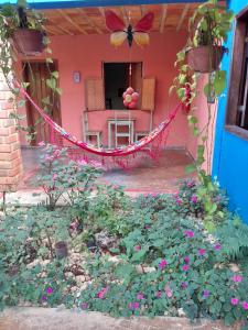 un porche de una casa con una hamaca y flores en Pousada Shangrilá, en Serra do Cipo