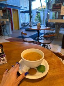 a woman is holding a bowl of soup on a table at Hotel Cidade Imperial in Petrópolis