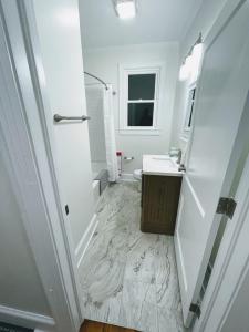 Baño blanco con lavabo y espejo en Renovated 1 Bedroom In Forest Hills - A, en Durham