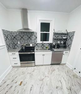 una cocina con armarios blancos y azulejos blancos y negros en Renovated 1 Bedroom In Forest Hills - A, en Durham