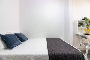 a bedroom with a bed with blue pillows and a table at Churruca Apartments! in Málaga +9 photos