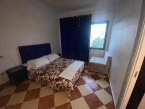 sypialnia z łóżkiem, krzesłem i oknem w obiekcie Complexe Jardins andalouse w mieście Tanger