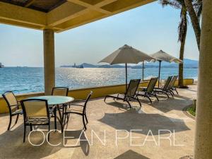 um pátio com cadeiras, mesas e guarda-sóis na praia em The Ocean Pearl Beachfront Infinity Pool Gym BBQ em Manzanillo