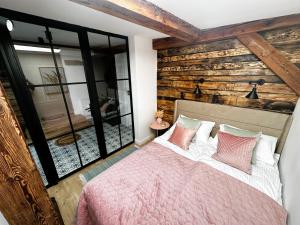 ein Schlafzimmer mit einem Bett und einer Holzwand in der Unterkunft Apartament Miodowy - DARMOWY PARKING - KlMATYZACJA - WIFI in Toruń
