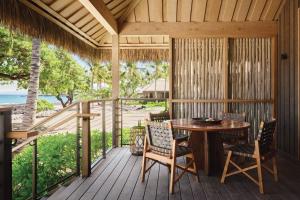 eine Holzterrasse mit einem Tisch und Stühlen darauf in der Unterkunft Kona Village A Rosewood Resort in Kailua-Kona