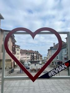 una ventana en forma de corazón con vistas a la ciudad en Evian appartement confort Vue lac et parking privé en Évian-les-Bains