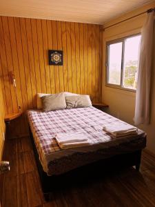 Cama en habitación con paredes de madera y ventana en ECO.MAR, en Punta del Diablo