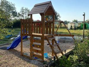 a wooden playground with a slide and a swing set at appartement in Beaupont