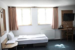 a hotel room with a bed and two windows at Gasthaus Hotel zum Kreuz in Stetten am Kalten Markt