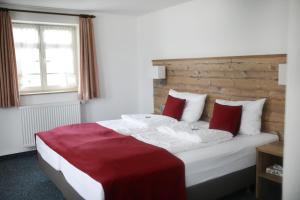 a bedroom with a large bed with red pillows at Gasthaus Hotel zum Kreuz in Stetten am Kalten Markt