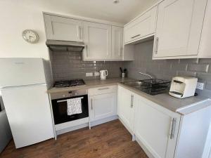 a kitchen with white cabinets and a stove top oven at Studio in Reading 