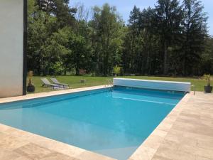 een zwembad in een tuin met twee stoelen bij logement avec accès piscine in Chaumont-sur-Tharonne