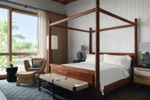 a bedroom with a canopy bed and a chair at Kona Village A Rosewood Resort in Kailua-Kona