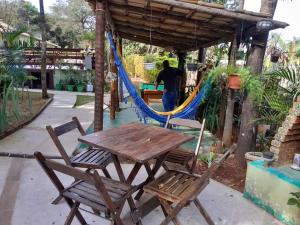 una mesa y sillas de madera y una hamaca en Pousada Alecrim, en Serra do Cipo