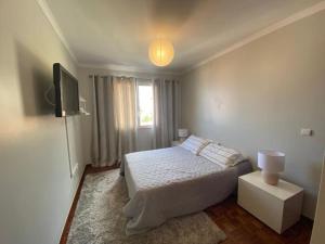 a white bedroom with a bed and a television at Residência Azevedo in Câmara de Lobos