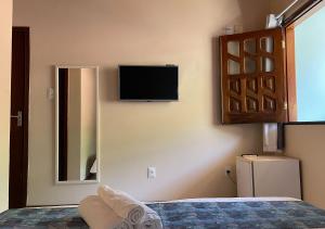 - une chambre avec une télévision murale et un lit dans l'établissement Pousada Estevao, à Morro de São Paulo