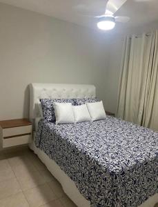 a bedroom with a bed with a blue and white comforter at Ap. Espetacular. À 5 minutos da praia. in Aracaju