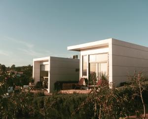 a white house with some chairs in front of it at La Cima del Valle in Valle de Guadalupe