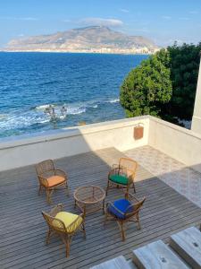 a group of chairs and tables on a deck with the ocean at San Liberale sul mare in Trapani