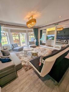 sala de estar con sofá, sillas y lámpara de araña en FINN VILLAGE "Raspberry Cottage" Private Garden, 6-seater Hot Tub, Firepit & Pizza Stove, en Glasgow