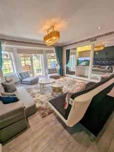 a living room with a couch and chairs and a chandelier at FINN VILLAGE "Raspberry Cottage" Private Garden, 6-seater Hot Tub, Firepit & Pizza Stove in Glasgow