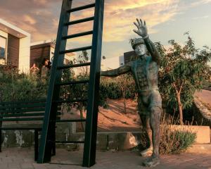 een standbeeld van een man die naar een ladder reikt bij La Cima del Valle in Valle de Guadalupe