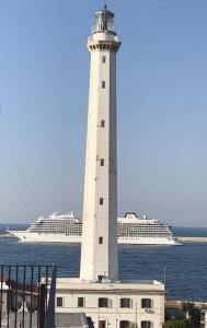 a lighthouse with a cruise ship in the water at Faro Sul Mare Luxury Apartment - Zona Fiera in Bari