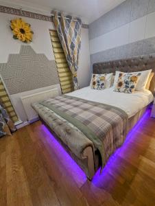 1 dormitorio con 1 cama grande con luces moradas en FINN VILLAGE "Raspberry Cottage" Private Garden, 6-seater Hot Tub, Firepit & Pizza Stove en Glasgow