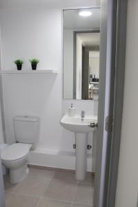 a white bathroom with a toilet and a sink at Lindo departamento vista al mar in Coquimbo +20 photos