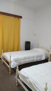 duas camas num quarto com uma cortina amarela em Nono Angelo Primero em San Pedro