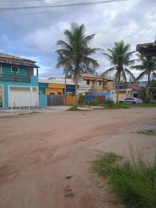 a dirt road with houses and palm trees in a town at Casa de Praia / Cabo Frio in Tamoios