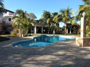 una piscina di fronte a una casa con palme di Villa Cocuyo Studios a El Cardón