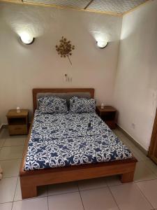 Schlafzimmer mit einem Bett mit einer blauen und weißen Bettdecke in der Unterkunft LES LOGIS DE NOUVELLE ROUTE BASTOS in Jaunde