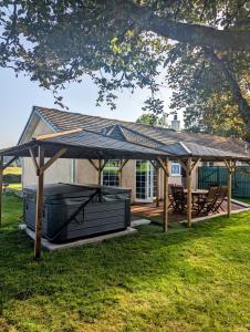 um grande pavilhão de madeira com uma mesa de piquenique e um banco em FINN VILLAGE "Raspberry Cottage" Private Garden, 6-seater Hot Tub, Firepit & Pizza Stove em Glasgow