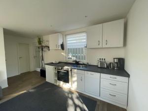 a kitchen with white cabinets and a sink at Ferienhaus Seekoje in Neustadt-Glewe +10 photos