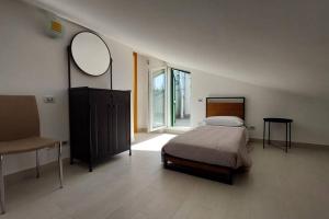 una camera con letto, specchio e sedia di Dimora Mirtilla - alloggio, max 4 posti letto. a Petacciato
