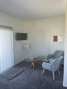 ein Wohnzimmer mit einem Stuhl und einem Tisch in der Unterkunft Wander Inn in Kaitaia