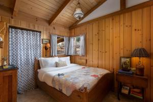 1 dormitorio con 1 cama en una habitación con paredes de madera en 056 - Beaumont Hideaway, en Big Bear City
