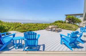 a group of blue chairs and tables on a deck with the beach at Sandpiper Retreat in Waldport