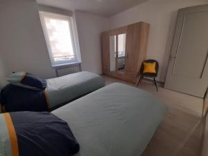 sypialnia z 2 łóżkami i żółtym krzesłem w obiekcie Gîte le Séquoia w mieście Sélestat
