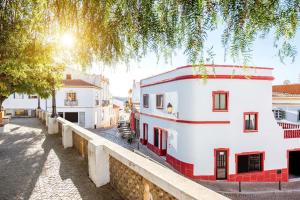 un edificio blanco con adornos rojos en una calle en Casa Cecilia Apartment Algarve, en Alte