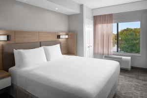 um quarto com uma grande cama branca e uma janela em SpringHill Suites by Marriott Grand Rapids Airport Southeast em Cascade