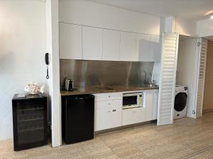 uma cozinha com armários brancos e um frigorífico preto em Oasis Rooftop Spa Apartment em Noosa Heads