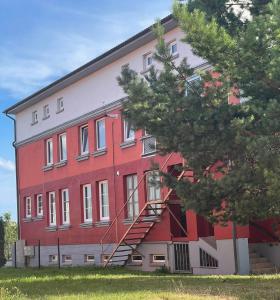 a red building with a staircase on the side of it at Apartamentai Jums in Telšiai