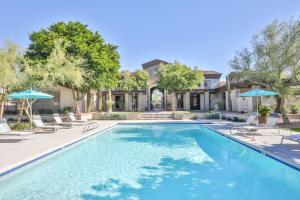 a swimming pool with chairs and umbrellas in front of a house at Luxury Vacation Rentals by Meridian CondoResorts in Scottsdale