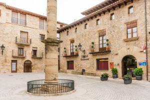 a large stone building with a column in front of it at Hotel Villa de Cretas in Cretas