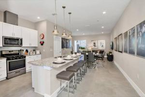 a kitchen with a large island with a bar with chairs at New Awesome decorated dreamhouse in Orlando