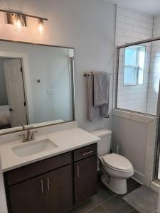 a bathroom with a sink and a toilet and a mirror at The Alamo Riverwalk Pearl Modern 4 Bedroom Home in San Antonio