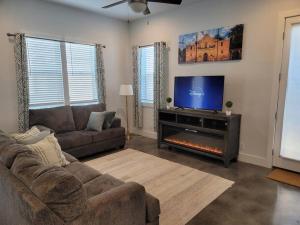 a living room with a couch and a flat screen tv at The Alamo Riverwalk Pearl Modern 4 Bedroom Home in San Antonio